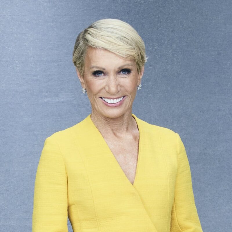 Person smiling in a yellow outfit against a gray background.