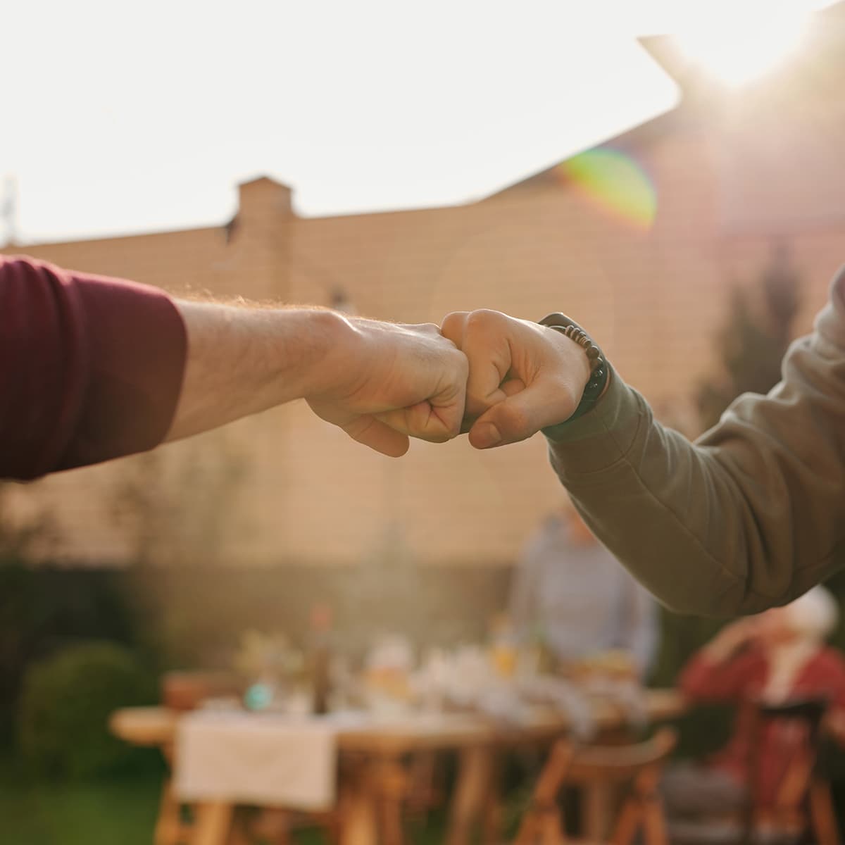 Two people fist bumping at an outdoor family gathering.