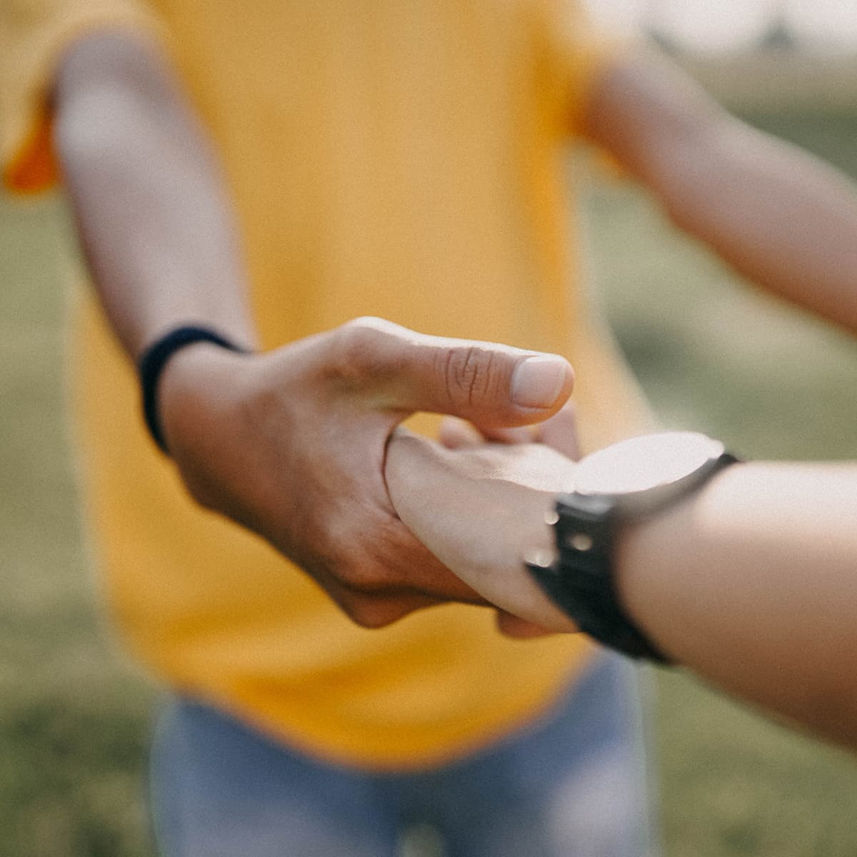 An out of focus image of two people holding hands in soft outdoor lighting.