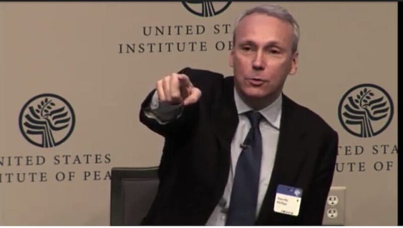 A man in a suit gestures while speaking at the United States Institute of Peace, with the organization's logo in the background.